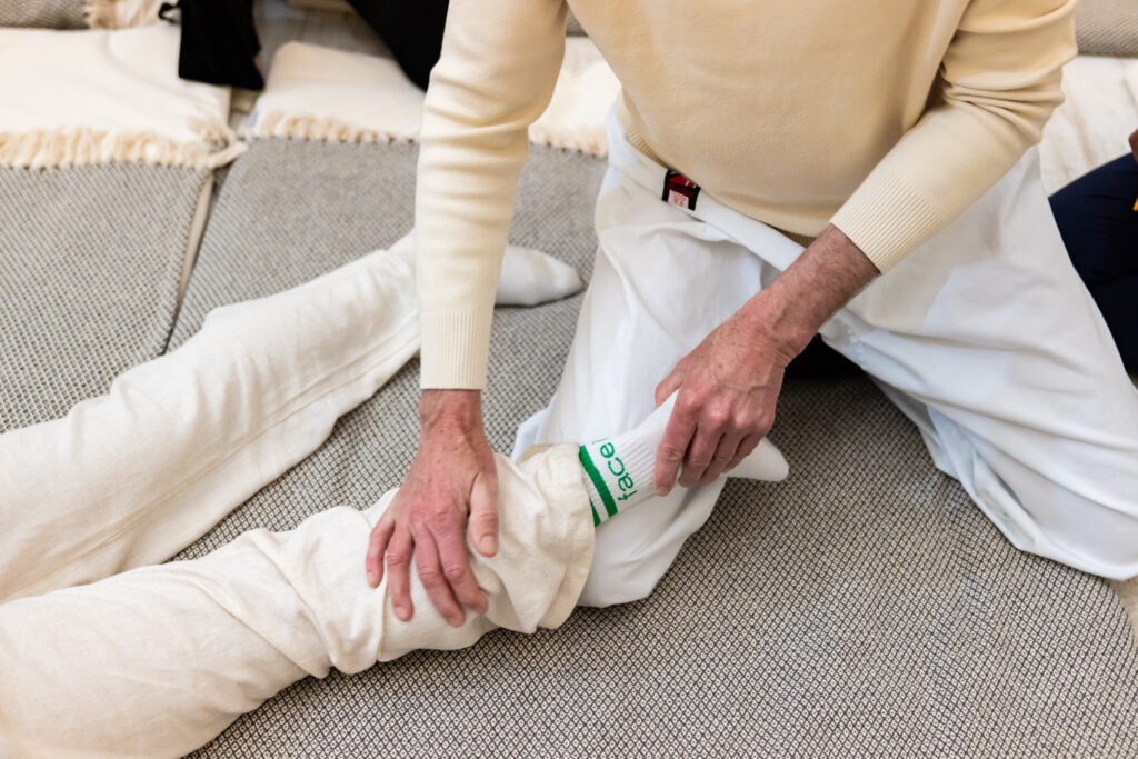 Handen geven rustige druk op het onderbeen tijdens een shiatsubehandeling